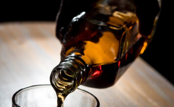 Man pouring whisky into a glass in a dark room