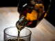 Man pouring whisky into a glass in a dark room